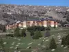 SuperDévoluy - Buildings of the ski resort, prairie, trees and mountain, in spring; in Dévoluy