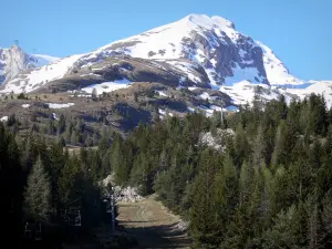 SuperDévoluy - Station de ski : télésiège (remontée mécanique), arbres et montagne au sommet enneigé, au printemps ; dans le Dévoluy