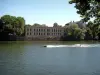 Thionville - Moselle river with a boat and people water-skiing, buildings and trees