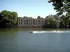 Thionville - River (Moezel) met een boot en de mensen waterskiën, gebouwen en bomen