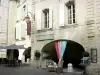 Uzès - Place aux Herbes : arcades (arceaux, couverts), façades de maisons, boutique et terrasse de restaurant