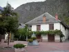 Valbonnais - Aldeia de Entraigues: praça com fonte, árvore e flores, casas da aldeia e montanha ao fundo