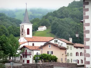 Vale do Aldudes - Torre sineira da igreja de Notre-Dame e casas na aldeia de Aldudes em um cenário verde