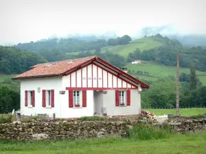 Vale do Aldudes - Casa com persianas e meia-timberings vermelho em um cenário verde