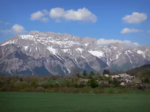 Vale do Champsaur - Pradarias, árvores e aldeola do vale Champsaur com vista para as montanhas Dévoluy