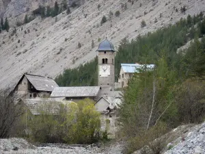 Vale do Clarée - Aldeia de Plampinet: torre sineira da igreja de São Sebastião, casas, árvores e encosta da montanha