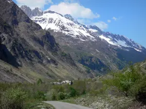 Valgaudemar - Tal des Valgaudemar: Strasse gesäumt von Bäumen, Häuserdächer eines Weilers und Berge mit schneebedeckten Gipfeln; im Nationalpark Ecrins (Ecrins Massiv)