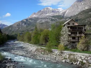 Vallouise - Bäume und Häuser am Flussufer, Berge überragen das Ganze; im Nationalpark Écrins