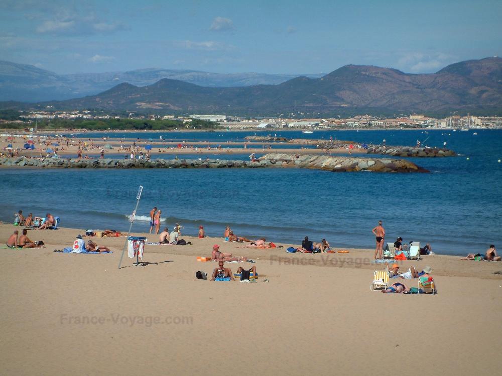 Guide du Var - Fréjus - Fréjus-Plage : plage de sable avec des estivants, mer méditerranée, rochers, golfe de Fréjus et collines en arrière-plan
