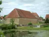 Villages du Berry - Étang parsemé de nénuphars, maisons berrichonnes en pierre, nuages dans le ciel