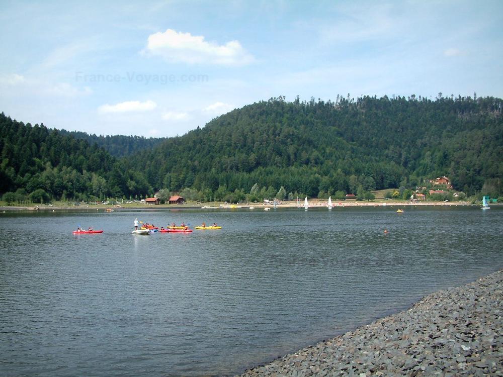 Guide des Vosges - Paysages des Vosges - Rive, lac avec kayaks et bateaux, arbres (forêt) en arrière-plan et nuages dans le ciel