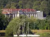 Wasserfläche von Vaires-sur-Marne - Katamaran (Doppelrumpfboot), Ufer bepflanzt mit Bäumen und Gebäude der ehemaligen Schokoladenfabrik Menier von Noisiel